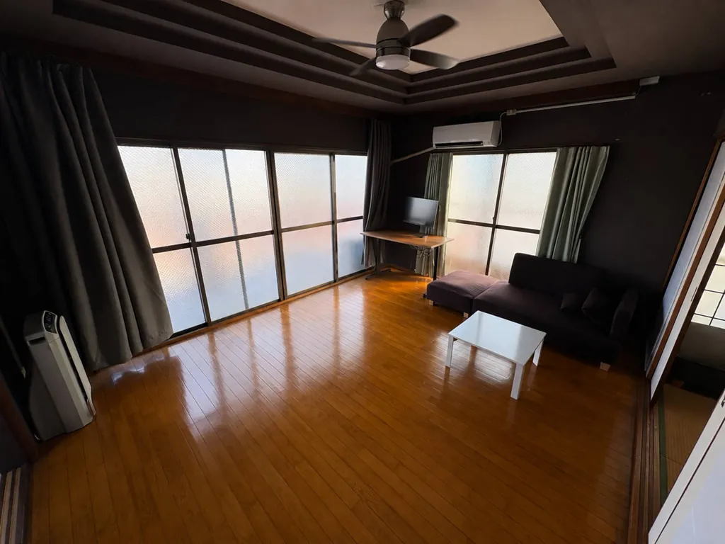 Living room with sofa and ceiling fan at Ben's Guesthouse Kobe