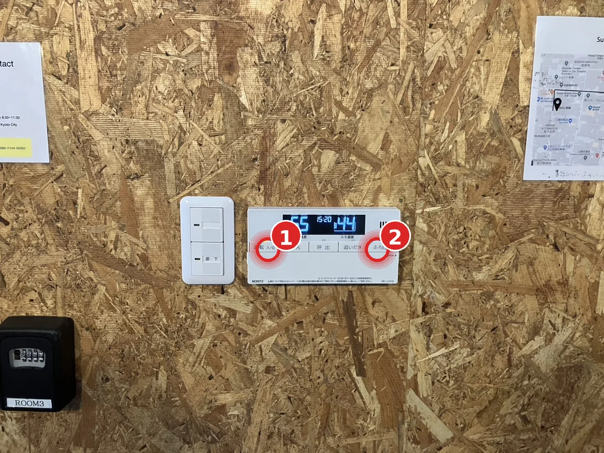 Foot-spa remote control panel mounted in the main hallway to the right of the key boxes — power button (1) on the left, ふろ自動 button (2) on the right